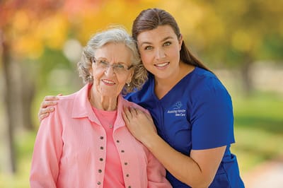 Caregiver posing with a resident outdoors in a colorful setting