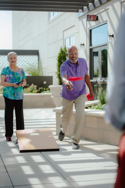 Residents playing cornhole in an outdoor area