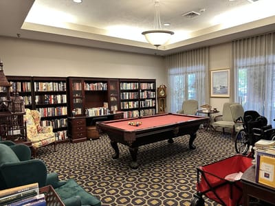 A cozy common area with a pool table and bookshelves