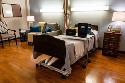 A well-furnished resident room with a hospital bed and seating area