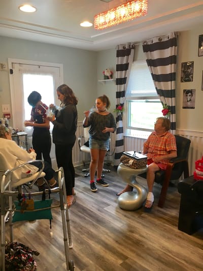 Residents enjoying a hairstyling activity with young visitors