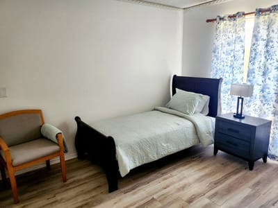 A private resident room with a bed and chair