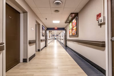 A corridor with doors and wall art in a nursing facility