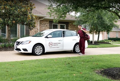 Healthcare worker approaching a vehicle in a residential area