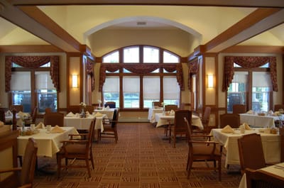 Dining room with tables and chairs arranged for residents