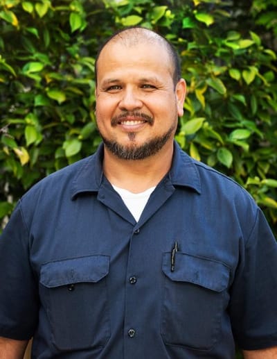 Staff member smiling in front of greenery