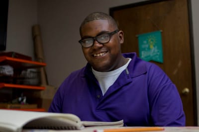 A smiling resident sitting at a table working on a project