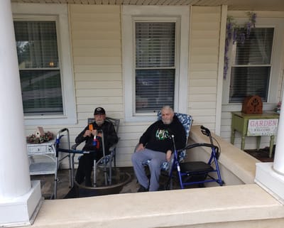 Two residents relaxing on a porch outside.