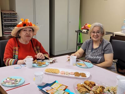 Two residents enjoying snacks at a table