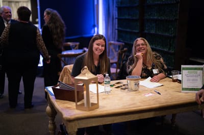 Two staff members at a registration table in a social event