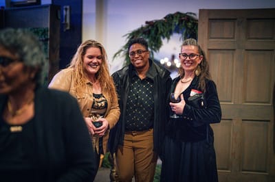Three women smiling together at a social event