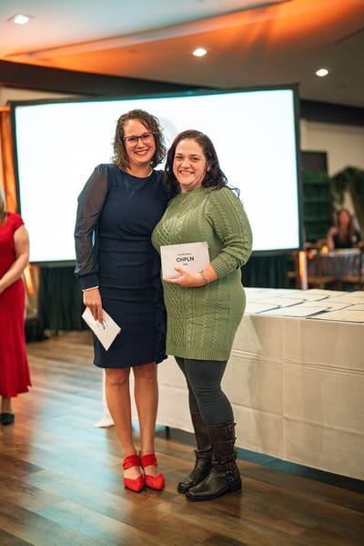 Two women smiling and posing at an award event