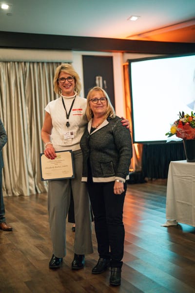 Two women celebrating an achievement with a certificate.