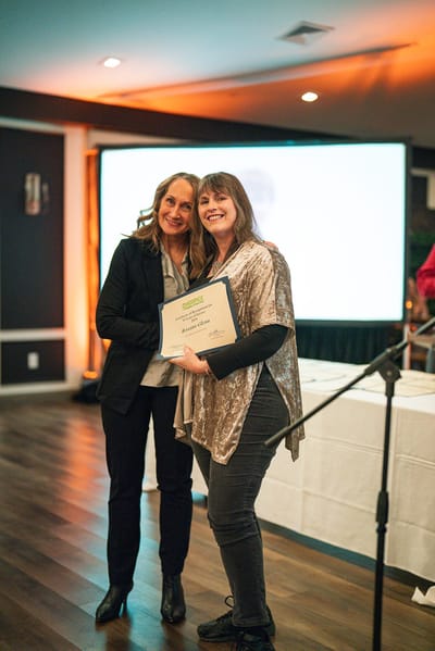 Two women at a ceremony holding a certificate