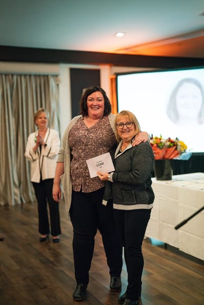 Two staff members celebrating an achievement at an event