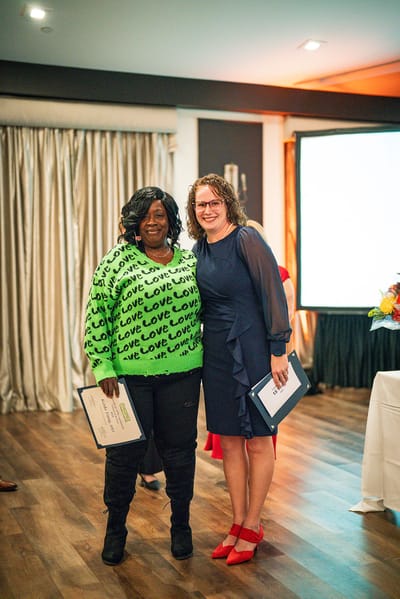 Two women holding certificates in an event setting