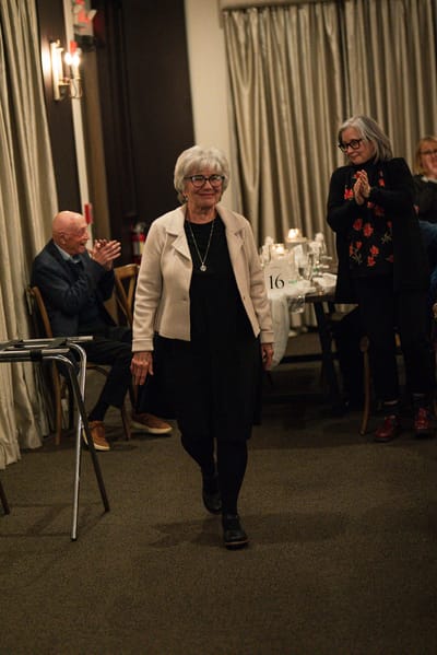 A resident walking during an event with applauding guests