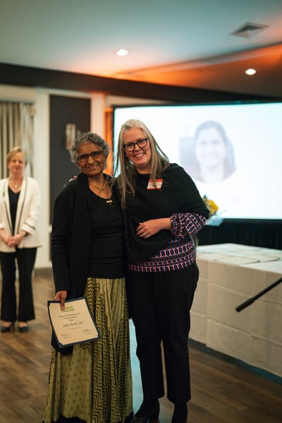 Two women at a celebration, holding an award