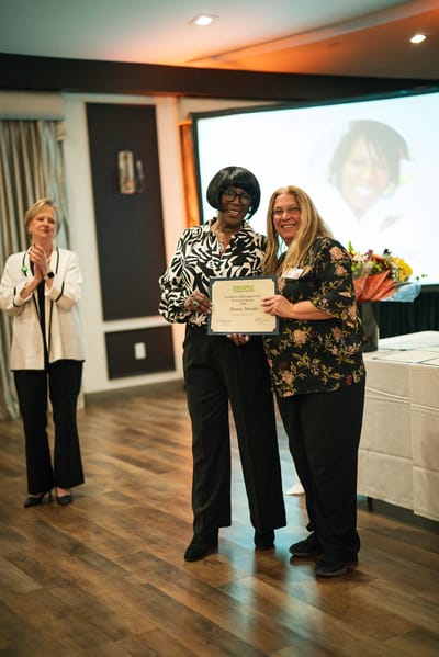 Staff celebrating a resident award presentation in a common area