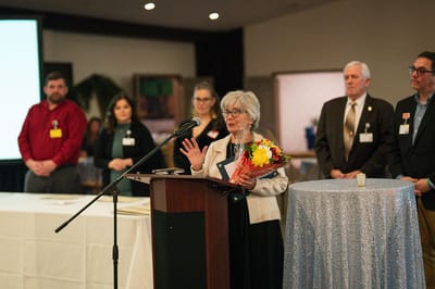 Resident speaking at a celebration event with staff present