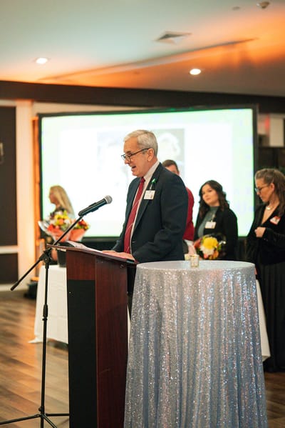 Speaker at a community event with staff in the background
