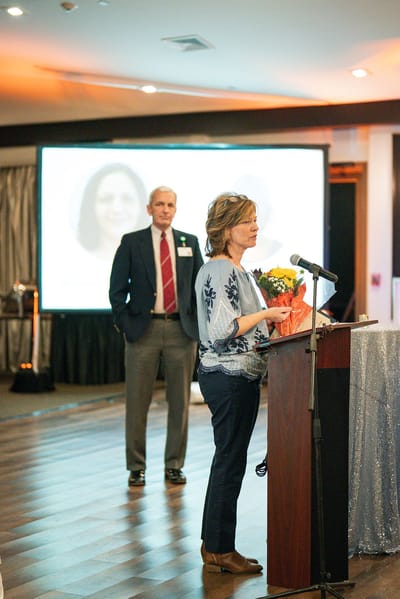 Speaker addressing an audience at an event with projector in background