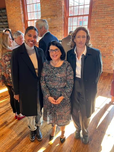 Three women posing together in a warm interior space
