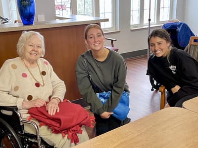 A resident and staff members smiling together in a common area