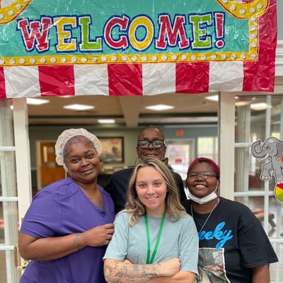Staff and residents smiling together under a welcome banner
