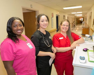 Three healthcare staff members in a facility hallway