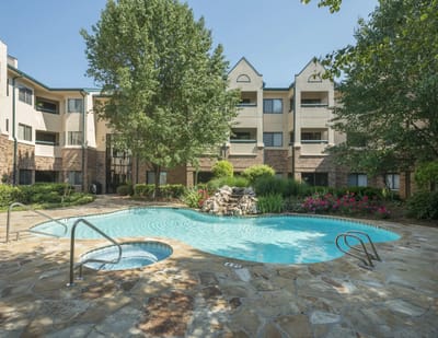 Outdoor pool area with landscaping and building in background