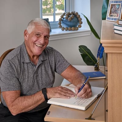 A smiling male resident writing in a notebook