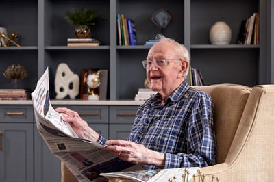 Senior resident enjoying a newspaper in a cozy chair