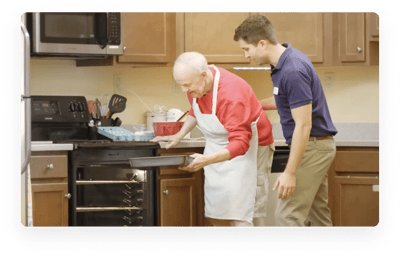 Senior resident baking with staff member in kitchen