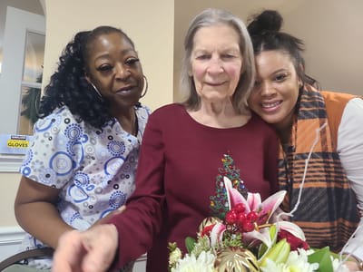 Staff and resident celebrating with flowers in an interior setting