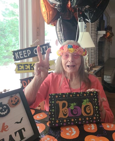 An elderly woman at a Halloween-themed table celebrating