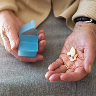 Hands holding medication and a pill organizer