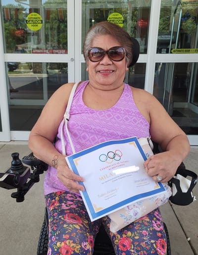 Resident holding a certificate outside the facility
