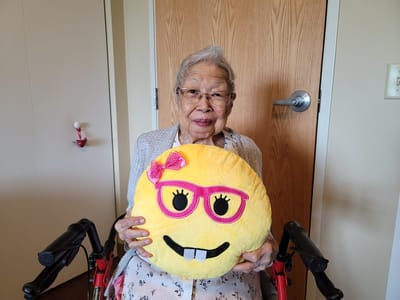 A resident holding a large emoji pillow in a cozy interior
