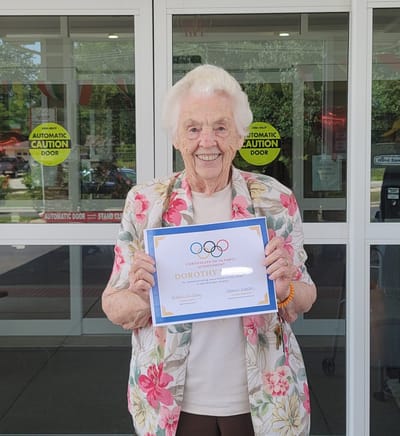Resident holding a certificate in front of the facility entrance
