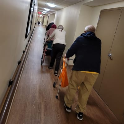 Residents using walkers in a hallway
