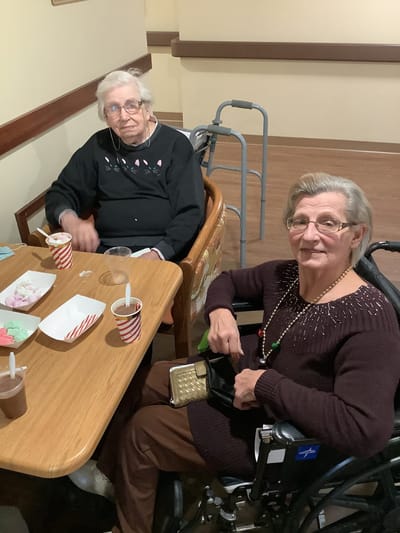 Two residents enjoying snacks at a table