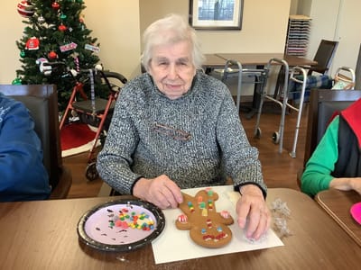 Resident decorating a gingerbread cookie in an activity room