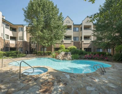 A serene outdoor pool surrounded by lush greenery and flowers.