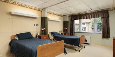 A clean and well-furnished resident room with two beds