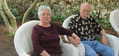 An elderly couple sitting outdoors in chairs
