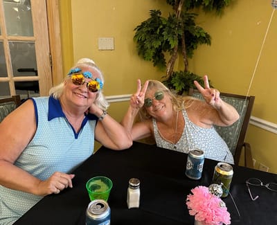 Two women smiling and posing indoors with drinks