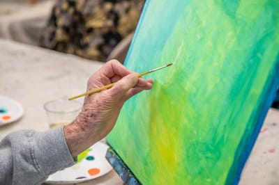A close-up of a hand painting on a canvas.