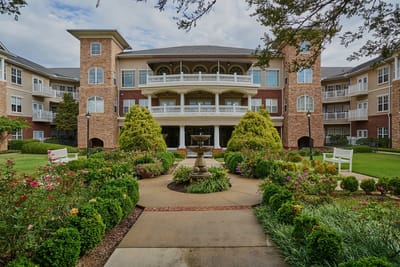 Exterior view of a nursing home with gardens and seating