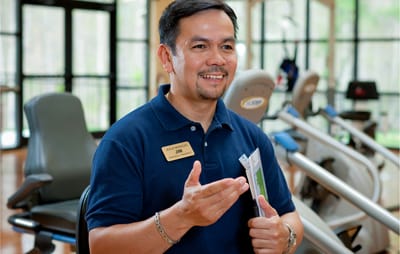 Staff member engaging with residents in a fitness room